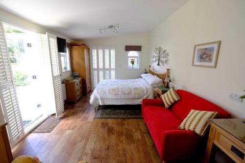 una camera con un letto e un divano rosso di The Garden Room a Woodbridge