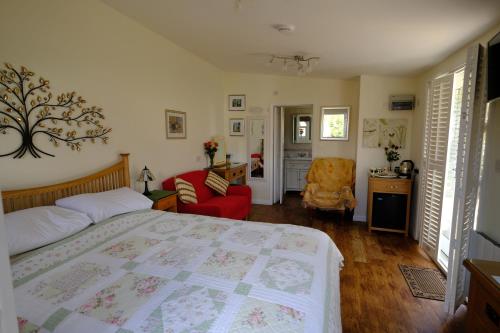 a bedroom with a bed and a red chair at The Garden Room in Woodbridge