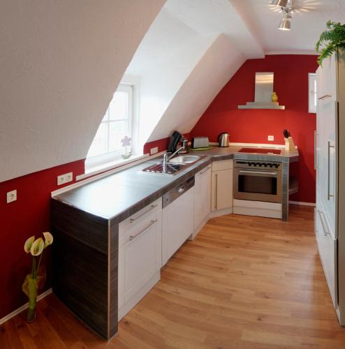 eine Küche im Dachgeschoss mit roten Wänden und einer Kücheninsel in der Unterkunft Appartement Stadtpartie in Suhl