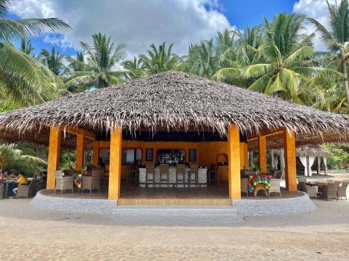 a hut with a straw roof on the beach at Coco Grove Beach Resort, Siquijor Island in Siquijor