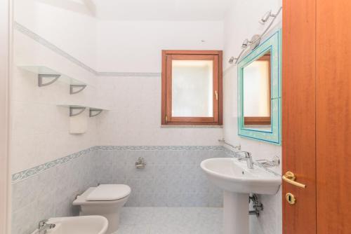 baño con lavabo y aseo y ventana en I Mirti di Porto Pozzo, en Santa Teresa Gallura