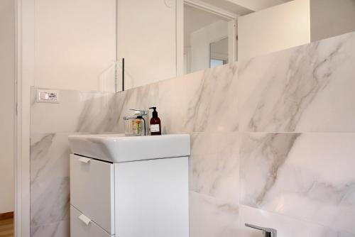 uma casa de banho branca com um lavatório e um espelho em Appartamento Oliva Villa Arber em Maccagno Inferiore