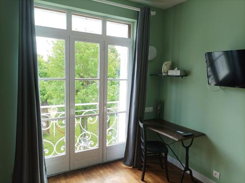 Zimmer mit einem Fenster, einem Schreibtisch und einem TV in der Unterkunft Le Relais des Roses- Chambres d'hôtes in Vatan