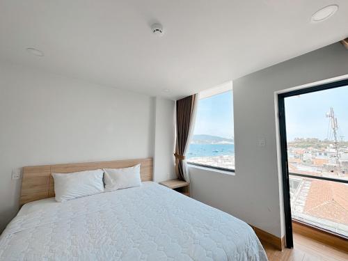 a bedroom with a bed and a large window at AQUA Seaview Hotel in Nha Trang