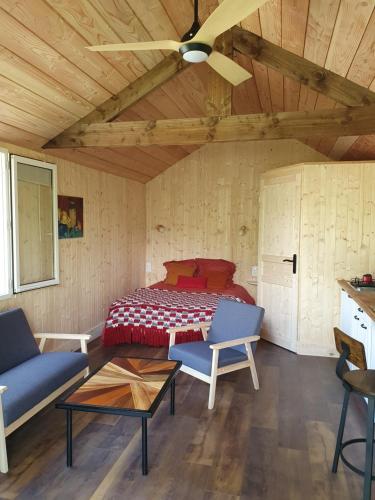 een slaapkamer met een bed, een bank en een tafel bij Studio en bois independant avec terrasse et jardin in Villevieille