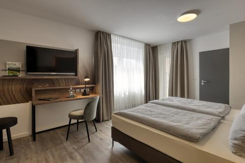 una camera d'albergo con letto, scrivania e TV di Hotel Imhof a Gemünden