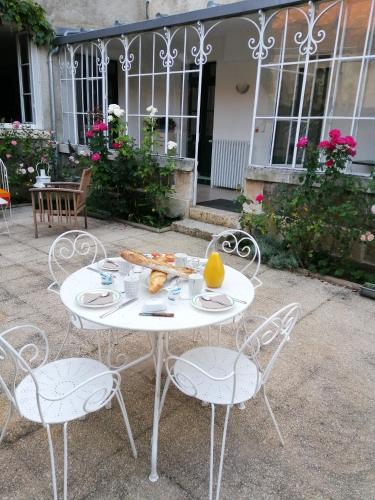 une table et des chaises blanches avec une assiette de nourriture dans l'établissement Le Relais des Roses- Chambres d'hôtes, à Vatan