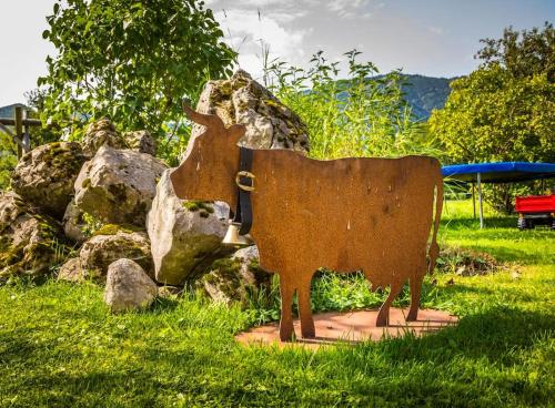 a statue of a cow sitting in the grass at Unterwöhrlehen in Faistenau