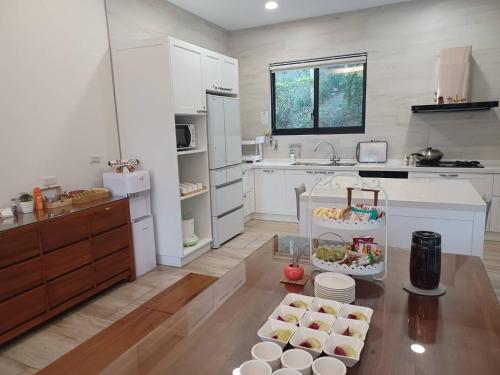 a kitchen with white cabinets and a table with dishes on it at 印象莊園包棟民宿,一日一組客人,依人數開房 in Xihu