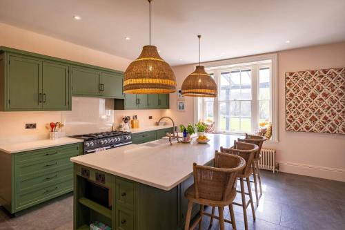 a kitchen with green cabinets and a kitchen island with chairs at Hazelhurst in Sway