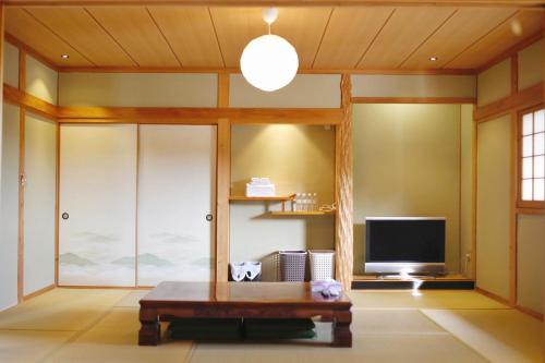 a living room with a table and a tv at 湯布院我楽珍民泊Yufuin Garakuchin in Yufu