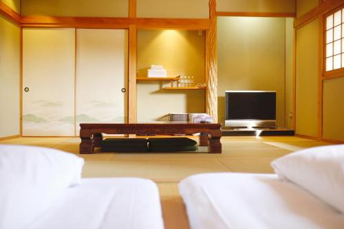 a living room with a couch and a tv at 湯布院我楽珍民泊Yufuin Garakuchin in Yufuin