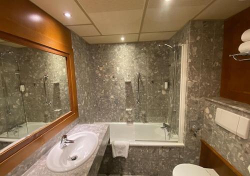 a bathroom with a sink and a shower and a tub at Plaza Hotel Capitole Toulouse - Anciennement-formerly CROWNE PLAZA in Toulouse
