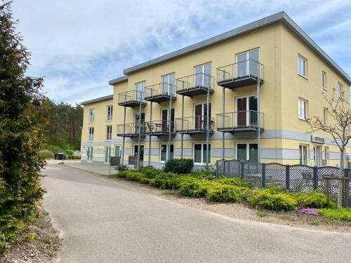 a large yellow building with balconies on a street at Küstenapartment 3 in Gelbensande