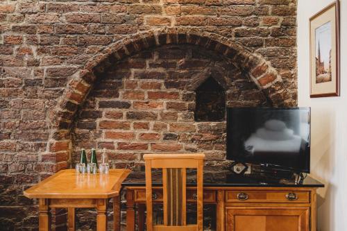 a room with a table and a tv and a brick wall at Hotel Solaris in Toruń