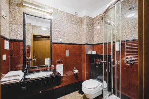 a bathroom with a toilet and a sink and a shower at Hotel Solaris in Toruń