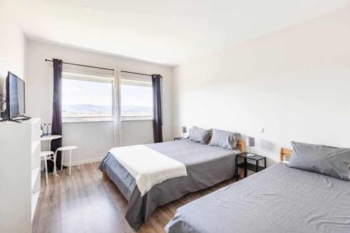 Bossa Nova GuestHouse في براغا: غرفة نوم بيضاء بسريرين ونافذة