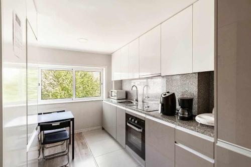a white kitchen with a counter and a window at Bossa Nova GuestHouse in Braga