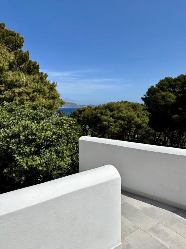 a white fence with trees and water in the background at Dimora delle Tonnare in Favignana