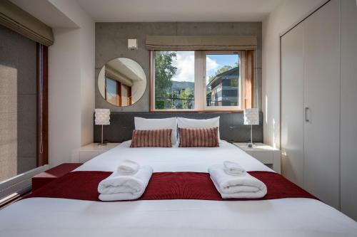 a bedroom with a large white bed with towels on it at Asobidokoro in Kutchan