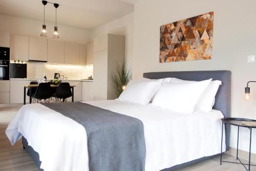 a bedroom with a large white bed and a kitchen at Aellō luxury apartments in Markopoulo