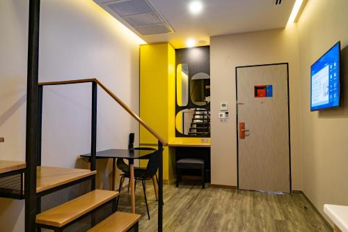 a small room with a table and a yellow wall at Hotel Z zpaze in Bangkok