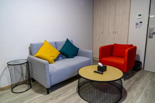 a living room with a couch and a red chair at Hotel Z zpaze in Bangkok