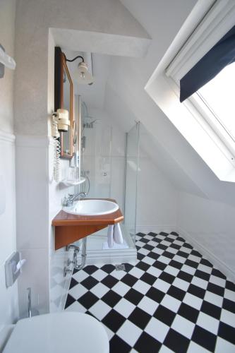 a bathroom with a sink and a black and white checkered floor at Akzent Hotel Franziskaner in Dettelbach