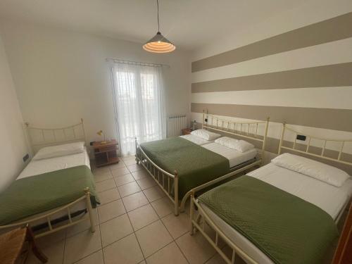 Habitación con 3 camas y ventana en Levante Beach via Grado - Agenzia Cocal, en Caorle