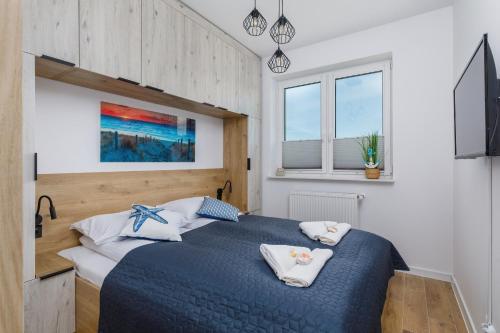ein Schlafzimmer mit einem blauen Bett und einem Fenster in der Unterkunft Sea Resort Kropli Bałtyku Apartment with Terrace by Renters in Darłowo