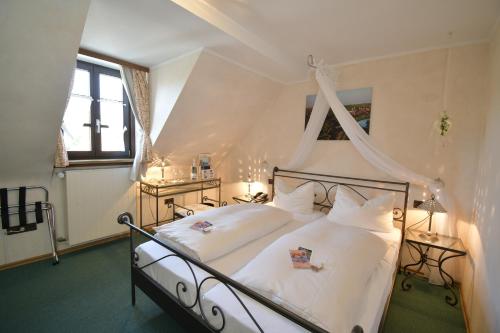 1 dormitorio con 1 cama blanca con dosel en Akzent Hotel Franziskaner, en Dettelbach