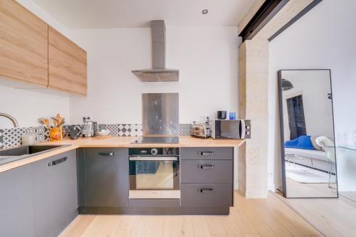 une cuisine avec un évier et une cuisinière four supérieur dans l'établissement La Casa 71 - Plein cœur de Bordeaux, à Bordeaux