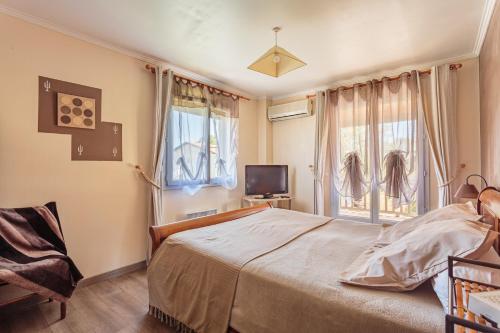 een slaapkamer met een bed, een tv en ramen bij Maison Urt - Charmante maison avec piscine in Urt