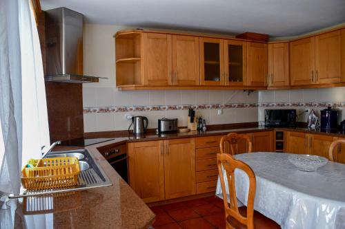 uma cozinha com armários de madeira e uma mesa com mesa; em Casa do Cantinho do Muro em São Vicente