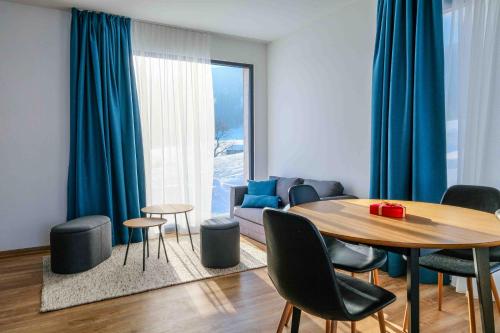 sala de estar con mesa y cortinas azules en Apartmány Trojice en Hynčice pod Sušinou