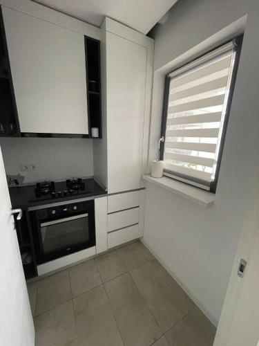 Il comprend une petite cuisine avec une cuisinière et une fenêtre. dans l'établissement Citta luxury apartment 75, à Bucarest