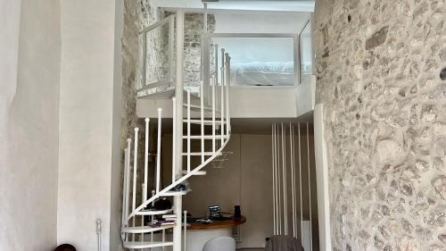 a spiral staircase in a room with a stone wall at La Maison Plume, Appart Boutique in Saint-Rémy-de-Provence