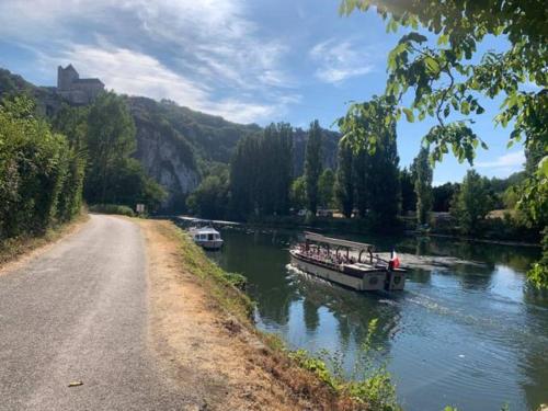 un bateau descendant une rivière à côté d'une route dans l'établissement Lovely House in Quiet Hamlet on banks of the Lot, à Saint-Martin-Labouval