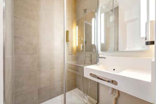 uma casa de banho com um chuveiro, um lavatório e um espelho. em B&B HOTEL Saintes em Saintes