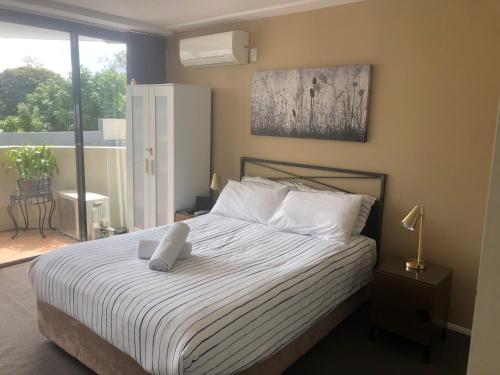 una camera da letto con un letto con lenzuola bianche e una finestra di SOUTH BRISBANE APARTMENTS Free Parking a Brisbane