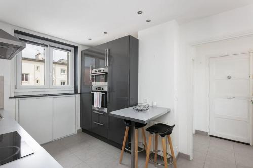 une cuisine avec des appareils électroménagers noirs et des tabourets dans l'établissement Une belle vue de Brest/T2 lumineux /Centre-Ville, à Brest