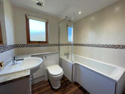 a bathroom with a sink and a toilet and a tub at Beautiful Norwegian Lodge in Kippford with Garden Pass the Keys in Dalbeattie