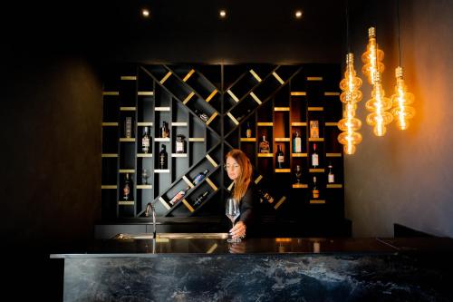 a woman standing at a counter in front of a wall of wine bottles at Golden Tree Hotel in Bruges