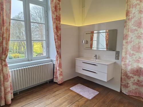 een badkamer met een wastafel, een spiegel en een raam bij Le Château des Portes 