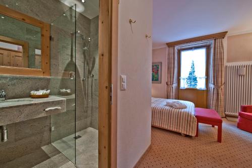 ein Bad mit einer Dusche, einem Waschbecken und einem Bett in der Unterkunft Parkhotel Margna Superior in Sils Maria