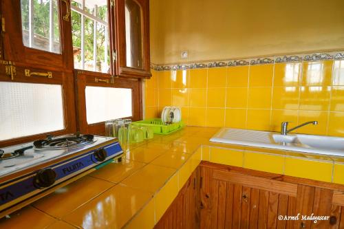 a yellow kitchen with a stove and a sink at An-tsaha Chambre d'hôtes in Fianarantsoa