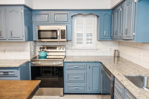 a blue kitchen with white appliances and blue cabinets at Cowry Acres - The First House Villa w Hot Tub in New Hope