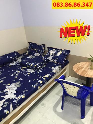 uma cama com lençóis azuis, uma mesa e uma cadeira em Nhà Nghỉ Năm Bé em Xuyên Mộc