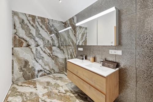 ein Bad mit einem Waschbecken und einem Spiegel in der Unterkunft Luxus Chalet Max in Glanz an der Weinstraße 