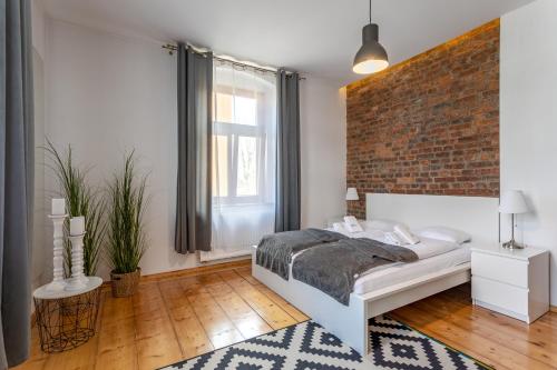 シュクラルスカ・ポレンバにあるApart-Invest Apartament Skandynawskiのレンガの壁、ベッド付きのベッドルーム1室